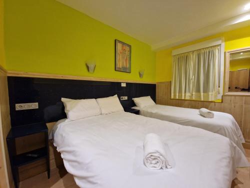 two beds in a room with yellow walls at Pension Izar Bat Guesthouse in San Sebastián