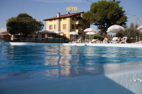 a pool at a hotel with people laying on the beach at Tenuta La Lupa in Castellina Marittima