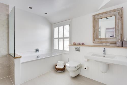 a bathroom with a toilet and two sinks and a mirror at The Idle Rocks in Saint Mawes