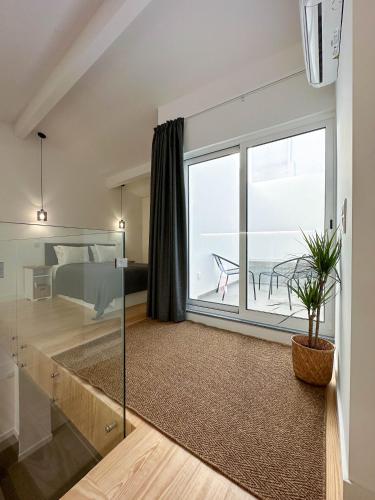 a living room with a large window and a bedroom at Apostolos Loft in Évora