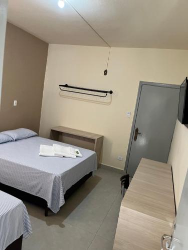 een kleine slaapkamer met 2 bedden en een spiegel bij Hotel Vila Rica in Maringá