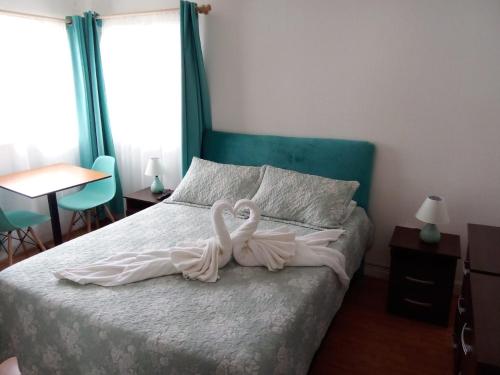 dois cisnes estão sentados em cima de uma cama em HOSTAL SUITE 1 Oriente 1075, Viña del Mar em Viña del Mar
