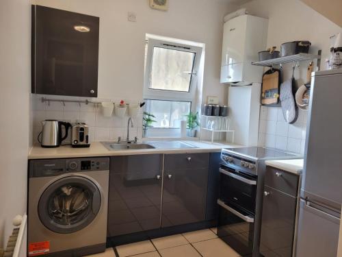 uma cozinha com uma máquina de lavar roupa e um lavatório em Stunning 1 bedroom apartment in London em Londres