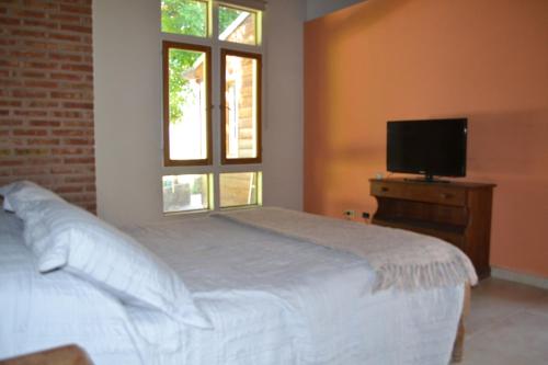 a bedroom with a white bed and a television at Coqueto departamento, Jardines del Rey in Neuquén
