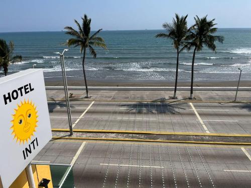 ボカ・デル・リオにあるHOTEL INTIのヤシの木が生えるビーチ前のホテルサイン