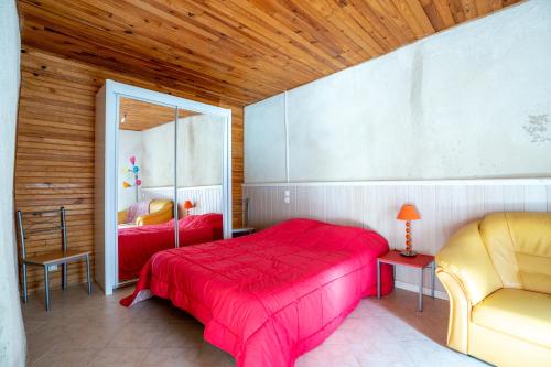 een slaapkamer met een rood bed en een stoel bij LaConciergerieJonzac, Résidence La Barberie in Saint-Martial-de-Vitaterne