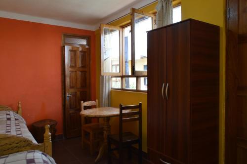 een kamer met een tafel, een kast en een slaapkamer bij Hostal Coronel Pedro Arraya in Tupiza