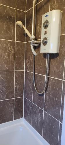 La salle de bains est pourvue d'une douche et d'un mur carrelé noir. dans l'établissement Entire 2 Bedroom House - Manchester, à Manchester
