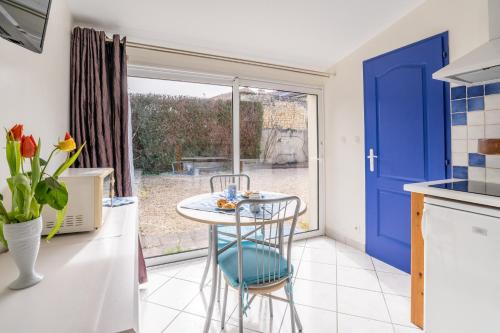 une cuisine avec une table et une porte bleue dans l'établissement Résidence Les Logis Du Brandard, à Jonzac