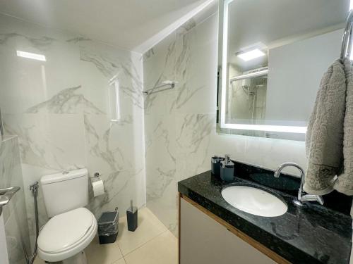 La salle de bains est pourvue de toilettes, d'un lavabo et d'un miroir. dans l'établissement Apartamento na melhor localização de Foz, à Foz do Iguaçu