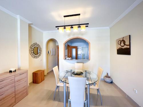 uma sala de jantar com uma mesa de vidro e cadeiras em Apartamento acogedor de 2 dormitorios a solo 150 m de la playa Sabinillas, Manilva em San Luis de Sabinillas