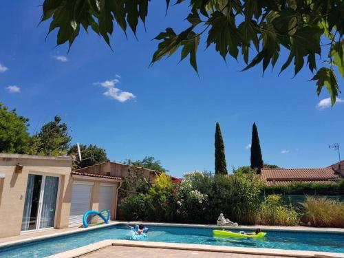 uma piscina com duas pessoas numa casa em L'Abri Côtier, villa avec piscine au coeur des vignes em Caux