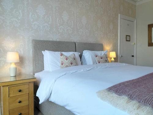 a bedroom with a large white bed with two lamps at Clarence House in Keswick