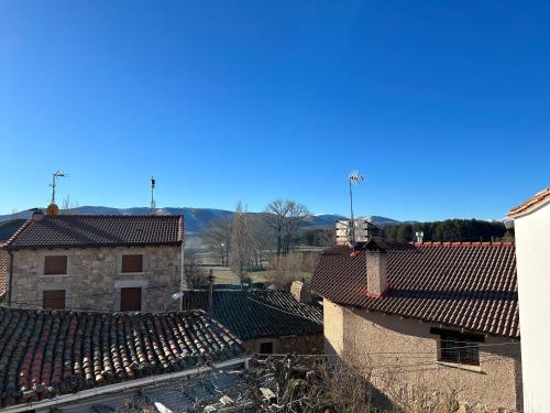eine Luftansicht der Dächer von Gebäuden mit Bergen im Hintergrund in der Unterkunft El Desván de Gredos in Navarredonda de Gredos
