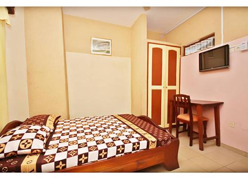 a bedroom with a bed and a table and a television at Amy's Hotel in Lomé