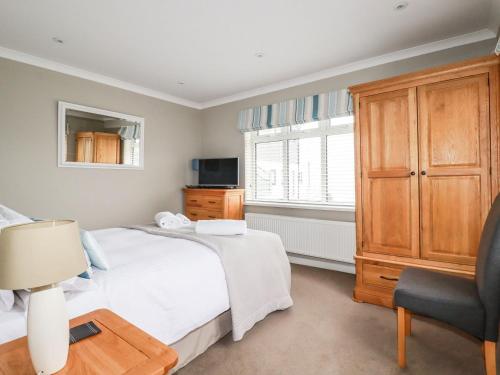 a bedroom with a bed and a chair and a window at Cormorant in Holywell Bay