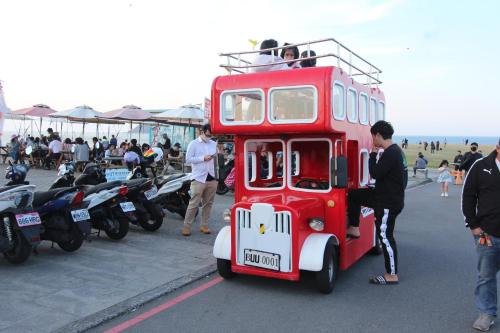 基隆的住宿－Sea Keelung，一辆红色双层巴士停在摩托车旁边