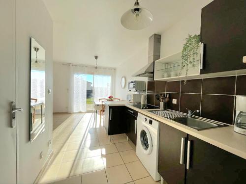 une cuisine avec un évier et une machine à laver dans l'établissement Logement thermale et de tourisme Les Acacias 2, à Jonzac