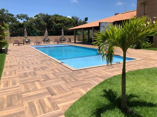 a swimming pool with a palm tree in a yard at Cantinho do Atalaia à 650 metros da praia - Seu conforto fora de casa in Salinópolis