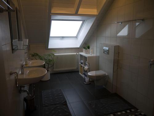 een badkamer met een wastafel en een toilet en een raam bij Ferienwohnung Bing in Rust