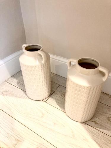 two white vases sitting on top of a wooden floor at Beautiful, 3 Bedroom Terrace, 2 minutes walk from Chester train station. in Chester