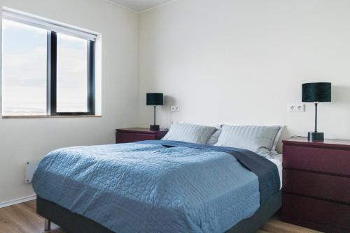 a white bedroom with a bed and a window at Skidbakki Guesthouse 