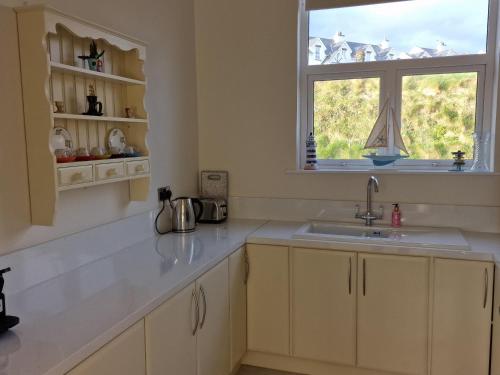 cocina blanca con fregadero y ventana en Beach House en Duncannon