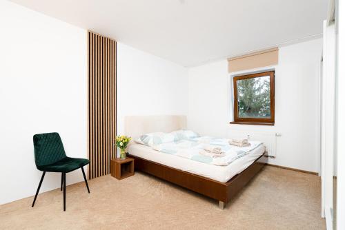 a bedroom with a bed and a chair and a window at Apartmány Jako doma in Pilsen