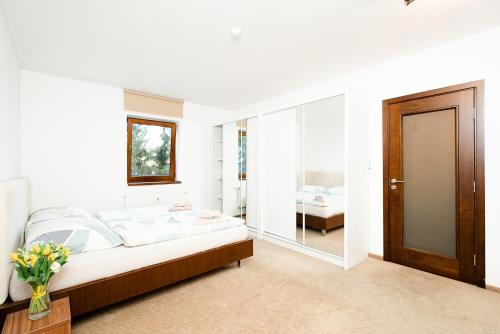 a white bedroom with a bed and a mirror at Apartmány Jako doma in Pilsen