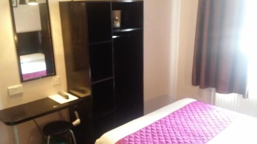 a bedroom with a bed and a dresser and a mirror at Arriva Hotel in London