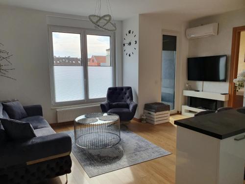 een woonkamer met een bank en stoelen en een tv bij Centar view lux in Novi Sad