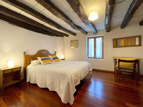 a bedroom with a large bed with white sheets and wooden floors at Casa Rural Erreteneko borda in Vera de Bidasoa