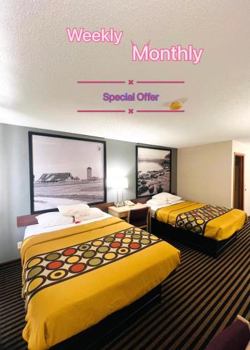 a hotel room with two beds and a sign that readsweekly monthly special offer at Super 8 by Wyndham Humboldt in Humboldt