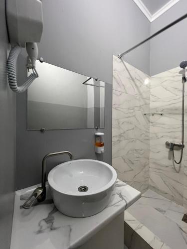 a white bathroom with a sink and a shower at Hotel NOMAD in Aktobe