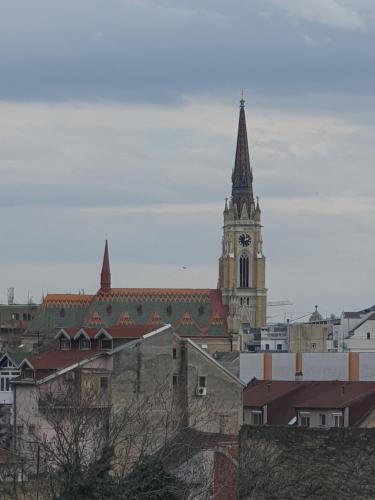 a church with a clock tower in a city at Centar view lux in Novi Sad
