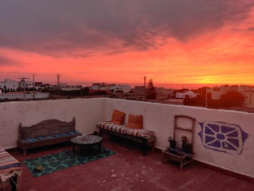 a balcony with couches and a view of a sunset at Hippie Chic - Room La Dune in Sidi Kaouki