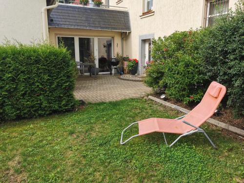 a pink chair sitting in the grass in front of a house at Ferienwohnung Haus Sonnenblick in Burkhardtsdorf