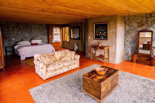 uma sala de estar com uma cama, um sofá e uma mesa em Nalanda Casa de Montaña em Patate