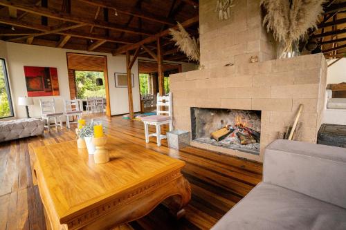 a living room with a wooden table and a fireplace at Nalanda SPA & Casa de Montaña in Patate