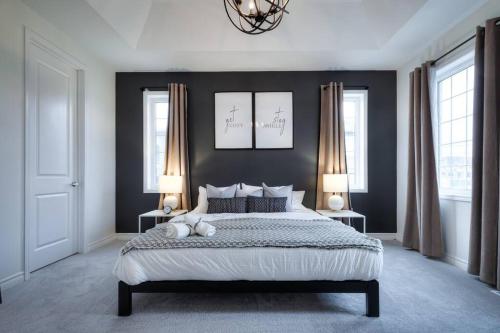 a bedroom with a large bed and two windows at Modern Comforts and Spacious Living 4B/3.5 Bath in Pickering