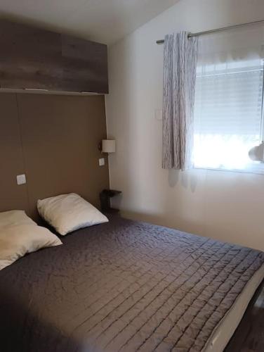 - une chambre avec un lit, une fenêtre et un couvre-lit dans l'établissement Petit coin de paradis, à La Teste-de-Buch