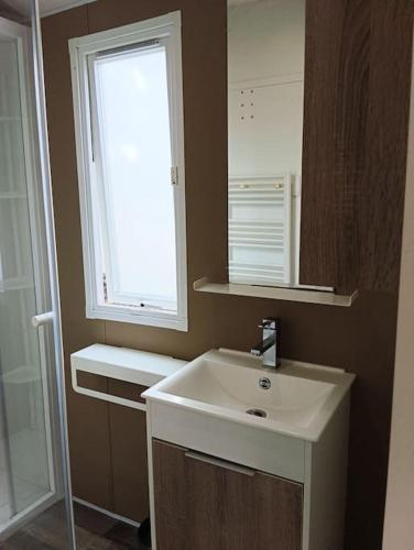 une salle de bain avec un lavabo blanc et une fenêtre dans l'établissement Petit coin de paradis, à La Teste-de-Buch