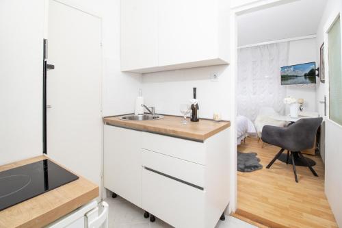 una cocina con armarios blancos y fregadero en Apartman BARBARA, en Vinkovci