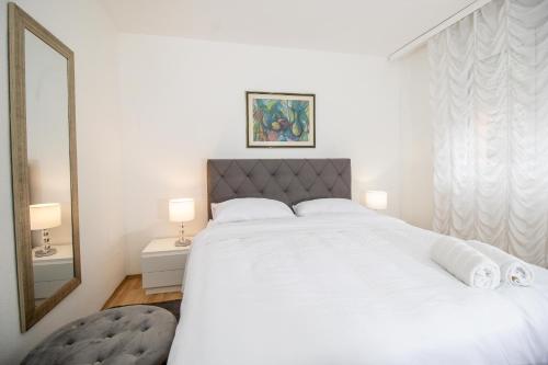 - une chambre avec un grand lit blanc et un miroir dans l'établissement Apartman BARBARA, à Vinkovci