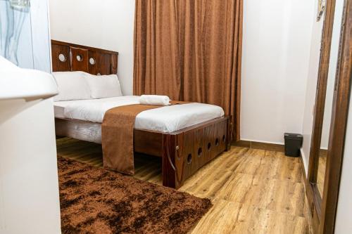 a bedroom with a bed with white sheets and wooden floors at MacCinray Villa Kisii in Kisii
