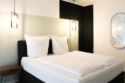 um quarto com uma cama com lençóis brancos e um espelho em Marvel-Apartment em Koblenz