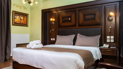 a bedroom with a large bed with a wooden headboard at Dellas Boutique Hotel in Kalabaka