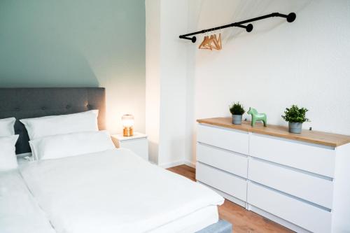 ein Schlafzimmer mit einem weißen Bett und einer Kommode in der Unterkunft 50qm Apartment in Krefeld zentral gelegen mit hohen Decken - BEUYS Apartments - Krefeld in Krefeld