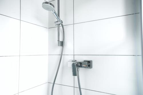 - prysznic w wyłożonej białymi kafelkami łazience w obiekcie 50qm Apartment in Krefeld zentral gelegen mit hohen Decken - BEUYS Apartments - Krefeld w mieście Krefeld
