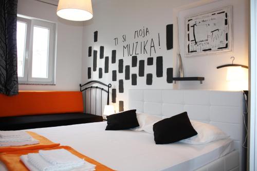 a bedroom with a white bed with an orange and black wall at Apartman Maria 1 in Rab